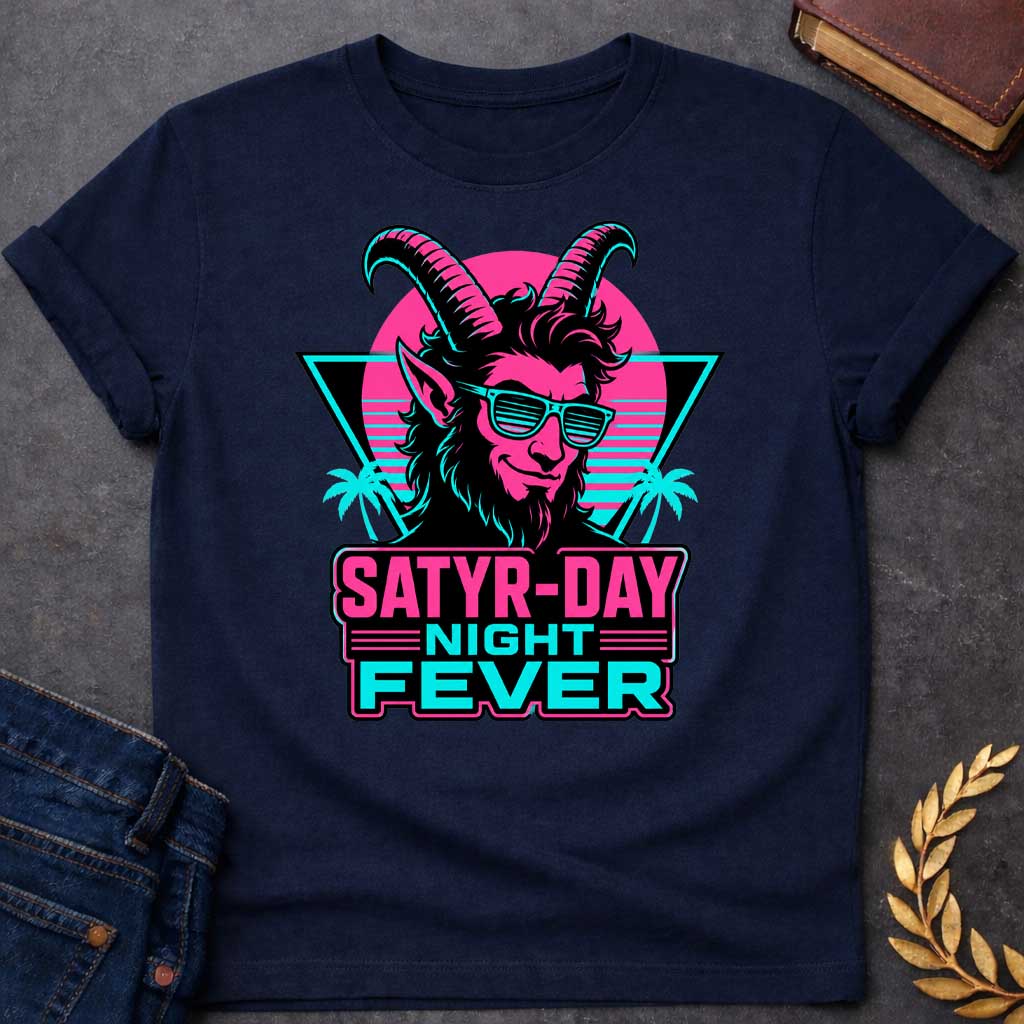 Navy T-shirt with a vibrant 1980s synthwave-style graphic for "satry-day night fever.jpg". It features a cool satyr with large horns, a smirk, and cyan shutter shades, illuminated in neon pink and black. The background shows a retrowave sunset grid, a black triangle, and palm trees. Below, the punny title "SATYR-DAY NIGHT FEVER" is displayed in bold neon pink and cyan block lettering against a dark badge