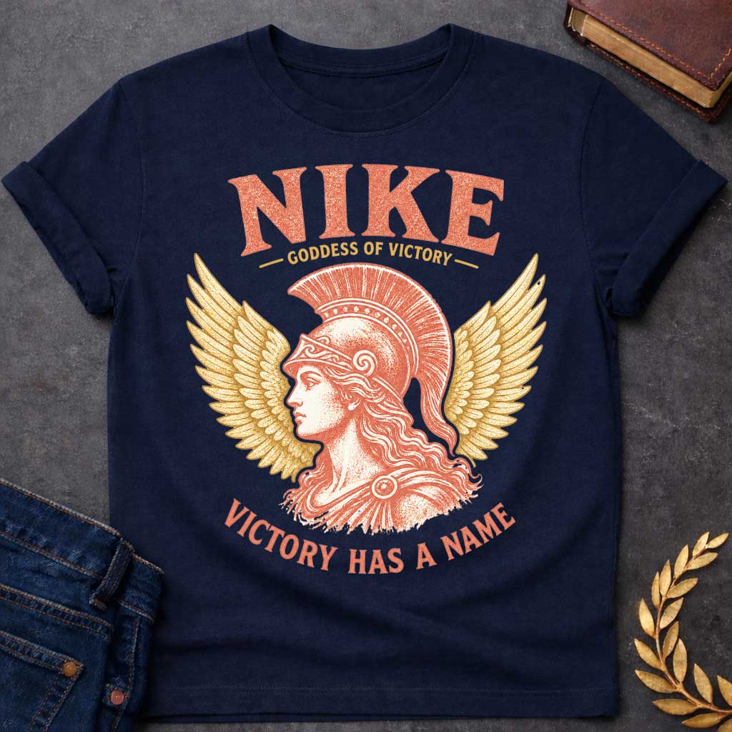 Navy t-shirt with a Vintage Nike Greek mythology design featuring the goddess of victory in profile wearing a classical crested helmet, framed by large golden wings. Distressed terracotta and gold artwork includes the text “Nike,” “Goddess of Victory,” and “Victory Has a Name,” celebrating strength, triumph, and ancient Greek mythology.