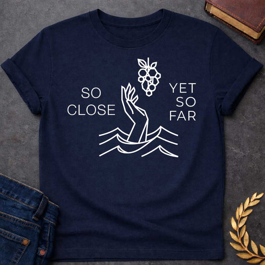 Navy t-shirt with A minimalist, geometric line-art design. Rendered in crisp white lines, a stylized hand reaches out from geometric water waves toward a cluster of grapes hanging above it. Simple, thin sans-serif text flanks the central illustration, with "SO CLOSE" stacked on the left and "YET SO FAR" stacked on the right.