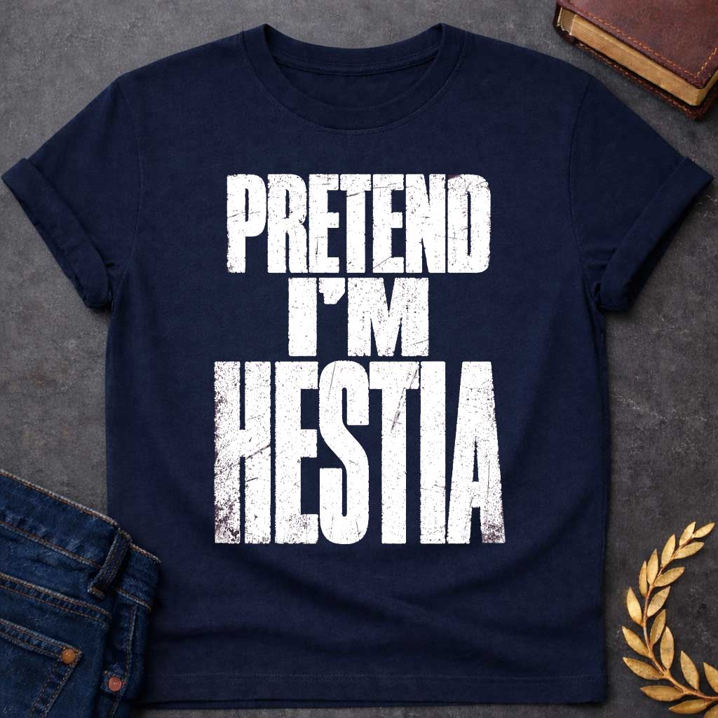 Navy t-shirt with a Pretend I’m Hestia Greek mythology design featuring bold distressed white typography on a transparent background. The stacked text reads “PRETEND I’M HESTIA” in a rugged vintage block font, creating a humorous design inspired by Hestia, the Greek goddess of the hearth, home, family, and domestic life.