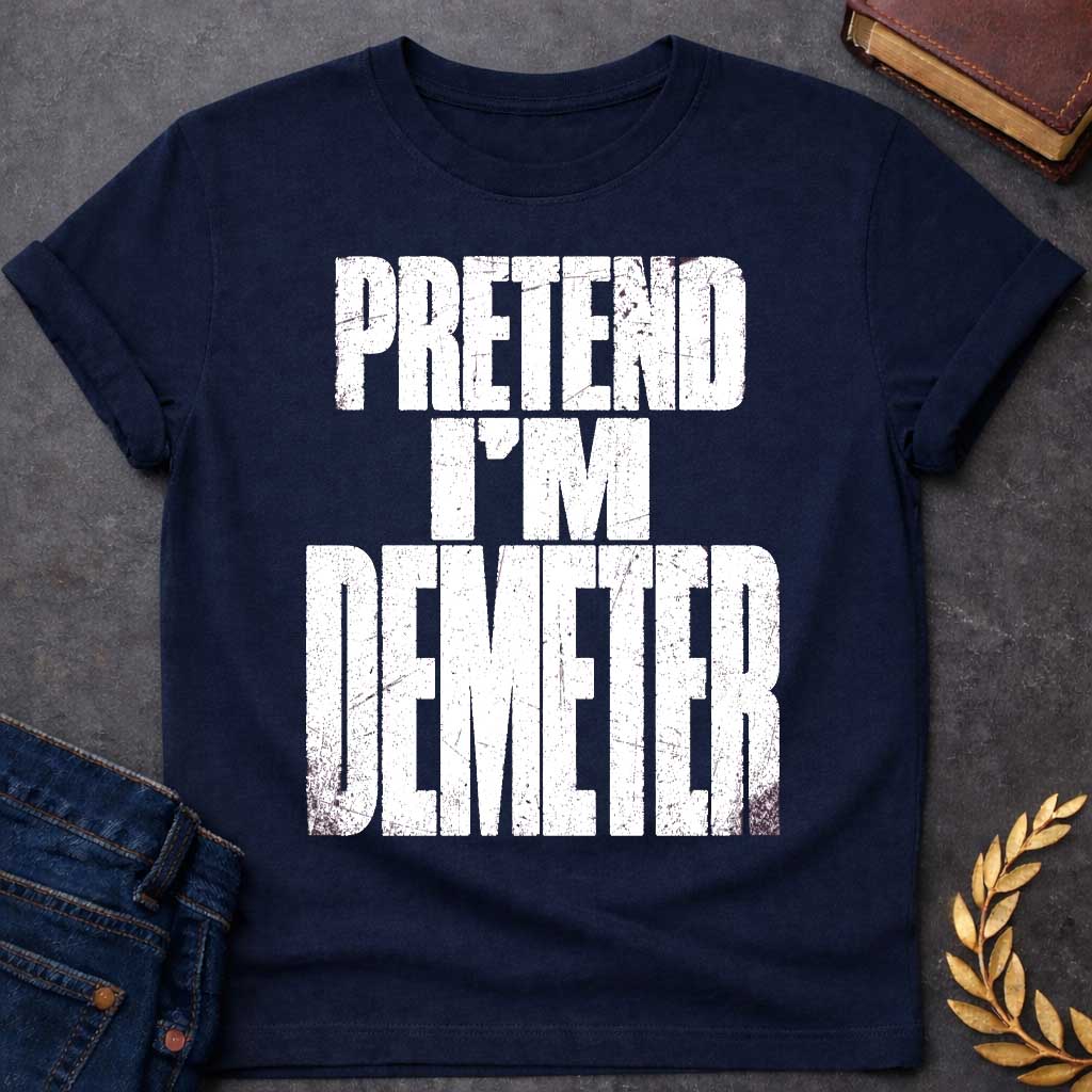 Navy t-shirt with a Pretend I’m Demeter Greek mythology design featuring bold distressed white typography on a transparent background. The stacked text reads “PRETEND I’M DEMETER” in a rugged vintage block font, creating a humorous design inspired by Demeter, the Greek goddess of agriculture, harvest, grain, fertility, and the earth.