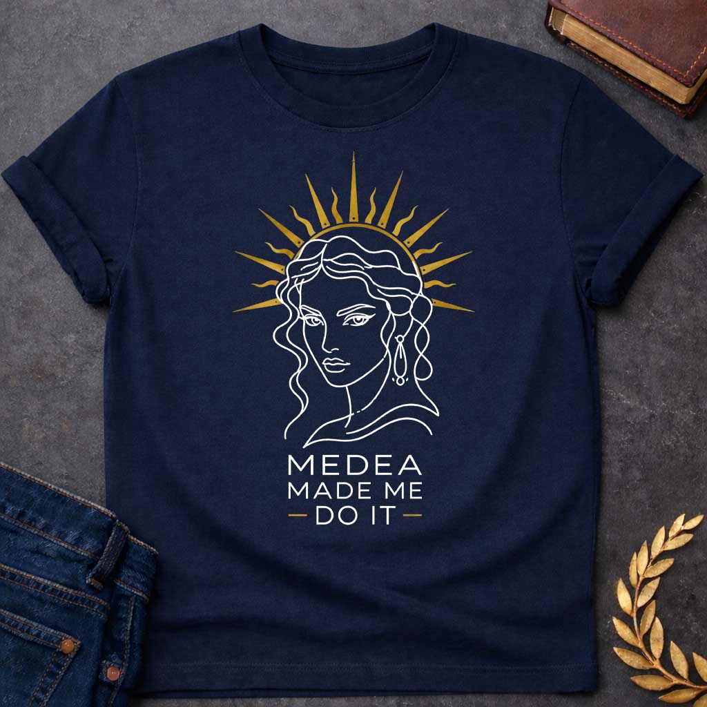 Navy T-shirt with a Minimalist line art portrait of Medea with wavy hair and drop earrings, framed by a golden radiating sun halo. Black and white design with gold accents. Text reads 'Medea Made Me Do It.' Humorous reference to blaming the legendary Greek sorceress for chaotic or destructive actions. Celebrates Medea's infamous power and magical influence with tongue-in-cheek blame attribution.
