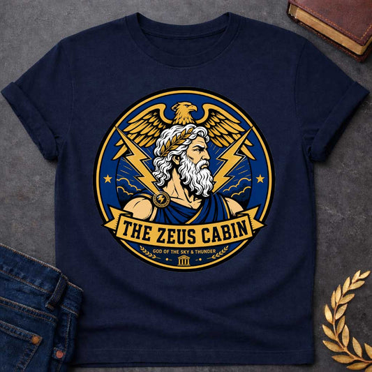 Navy t-shirt with a Zeus Greek mythology cabin design featuring the bearded god of the sky and thunder with a laurel crown, golden eagle, lightning bolts, storm clouds, and Greek temple symbol. Bold blue, gold, white, and black circular camp-style emblem includes the text “The Zeus Cabin” and “God of the Sky & Thunder.”