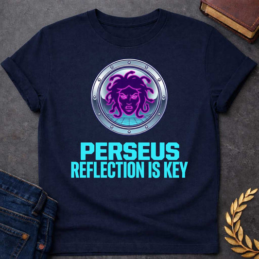 Navy t-shirt in synthwave style: a glowing neon-pink and purple Medusa face with snake hair sits inside a chrome porthole frame with rivets, backed by a retro grid floor and gradient sky. Bold cyan text below reads "Perseus" and "Reflection Is Key"