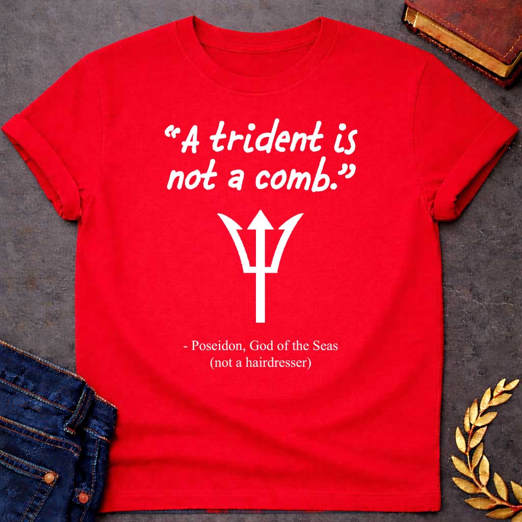 Red T-shirt graphic featuring a white handwritten-style quote reading "A trident is not a comb." above a flat white trident symbol, with the humorous attribution below in clean serif text reading "- Poseidon, God of the Seas (not a hairdresser)