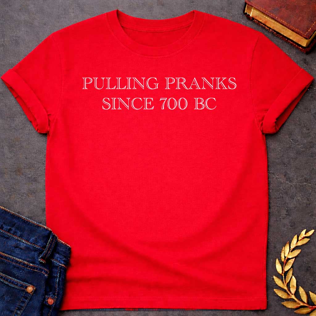 Red T-shirt graphic in white text featuring large outlined engraved-style serif text reading "Pulling Pranks Since 700 BC" — a humorous nod to Hermes, the Greek Messenger God and notorious trickster