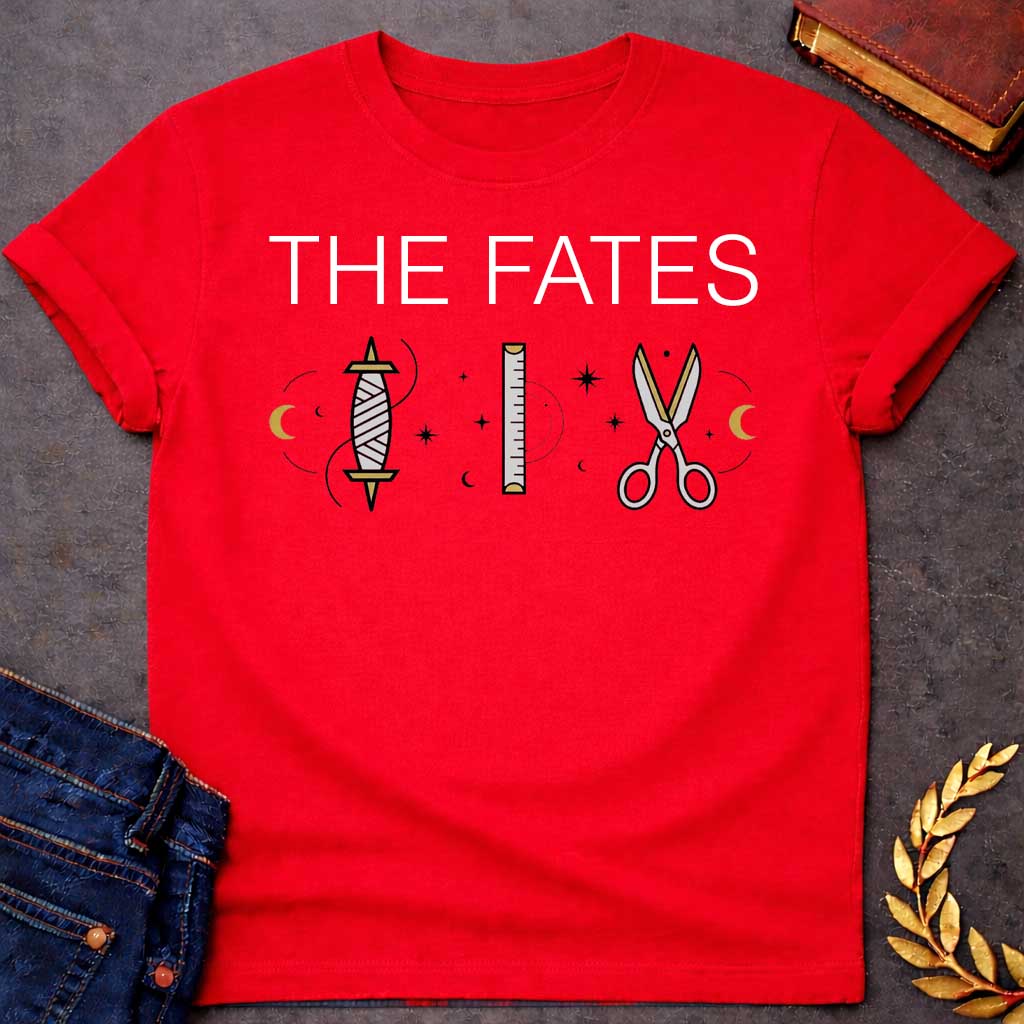 Red T-shirt graphic featuring large bold white text reading "The Fates" above three minimalist icons representing the tools of the Moirai, the Greek Fates — a spindle with thread, a measuring ruler, and a pair of scissors — each surrounded by subtle crescent moons and celestial star details, rendered in white and gold tones