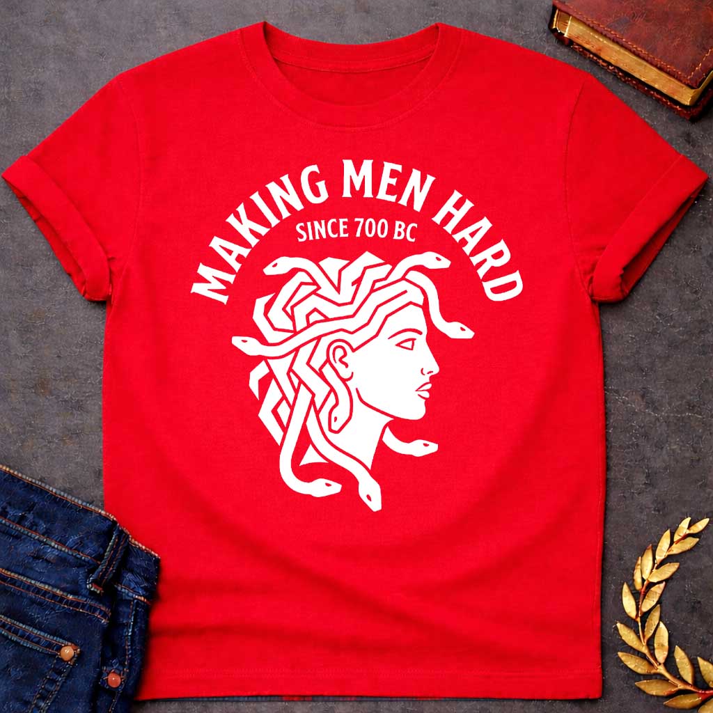 Red T-shirt graphic white featuring a bold flat graphic side-profile illustration of Medusa with snake hair, in a minimalist ancient Greek coin or seal style. Bold arched text above reads "Making Men Hard" with smaller text below it reading "Since 700 BC" — a witty double entendre referencing Medusa's mythological power to turn men to stone