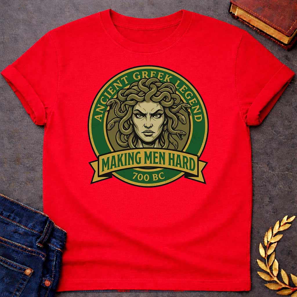 Red T-shirt graphic featuring a bold vintage badge design in forest green and gold. A fierce front-facing illustration of Medusa with coiling olive-toned snakes for hair and an intense glaring expression fills the circular center, with gold arched text reading "Ancient Greek Legend" around the upper border. A gold ribbon banner below the portrait reads "Making Men Hard" in green text, with "700 BC" below it — a witty double entendre referencing Medusa's mythological power to turn men to stone