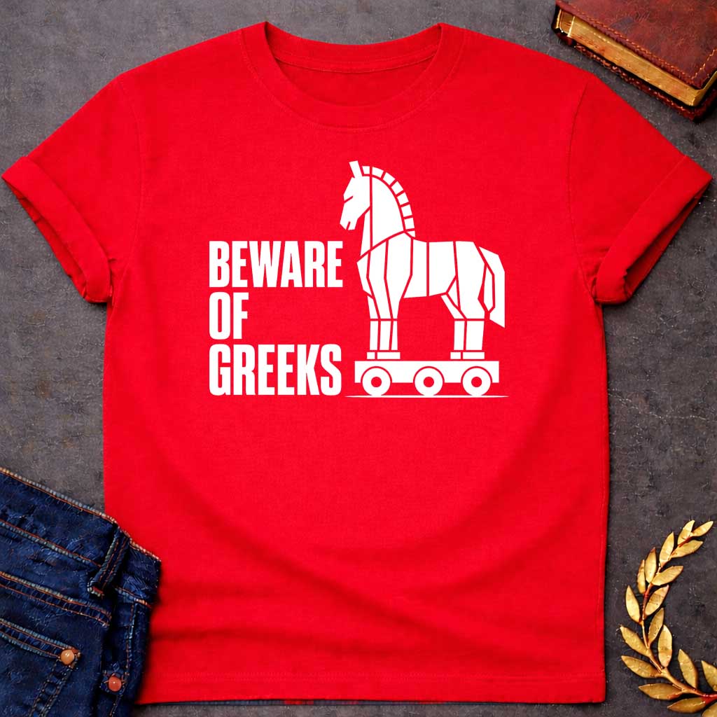 Red T-shirt with a graphic in white featuring bold condensed sans-serif text reading "Beware of Greeks" alongside a flat geometric white silhouette illustration of the Trojan Horse mounted on a wheeled platform — a humorous reference to the Greek legend of the Trojan War