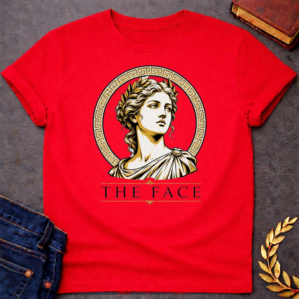 Red T-shirt with a classical Greek graphic featuring a gold and cream vector portrait of Helen of Troy in profile. She wears a golden laurel wreath and a traditional draped chiton, looking upward with a serene expression. The portrait is framed by a circular border with a gold Greek key (meander) pattern. Below the emblem, the text "THE FACE" is written in a clean, elegant black serif font between horizontal gold accent lines.