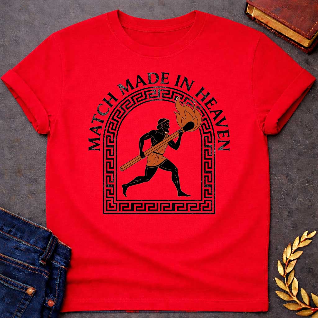Red T-shirt with A graphic in an ancient Greek Black-Figure pottery style featuring Prometheus running while carrying a massive, burning match stick. He is depicted in black silhouette with terracotta-orange details on his tunic and the flame. The figure is framed by a black Greek key meander arch. Above the design, the pun "MATCH MADE IN HEAVEN" is written in an arched, bold black serif font.
