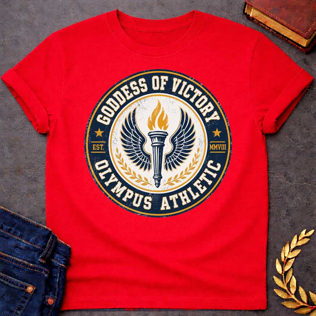 Red T-shirt with an Official athletic seal in navy blue, cream, and gold featuring a torch with large outstretched wings symbolizing Nike, the goddess of victory. Flames burn from the torch. Olive wreaths frame either side. Text reads 'GODDESS OF VICTORY' and 'OLYMPUS ATHLETIC' around the circular border with 'EST. MMVIII.' Distressed vintage texture and gold stars enhance the emblem. Celebrates athletic achievement and triumph.
