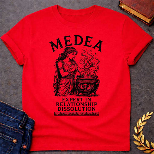 Red T-shirt with a Classical engraving of Medea, the legendary Greek sorceress, in flowing draped robes with Greek key pattern headband. She stirs a decorative cauldron with magical swirling smoke and stars rising dramatically from within. Black and white line art style with intricate detailing. Text reads 'Medea' above and 'Expert in Relationship Dissolution' below with Greek key border. Dark humor celebrates Medea's infamous reputation for magical vengeance and relationship destruction.