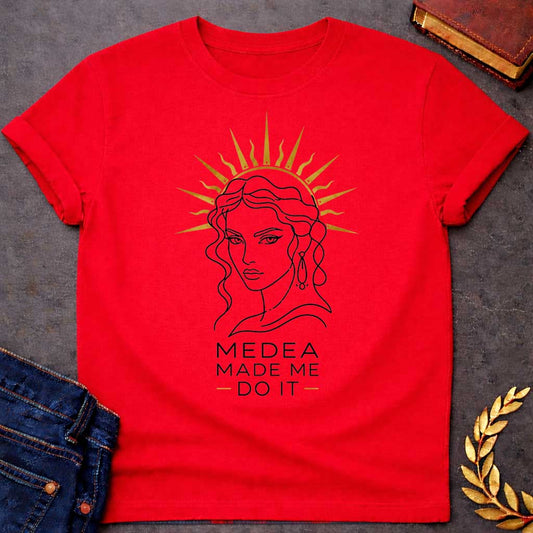 Red T-shirt with a Minimalist line art portrait of Medea with wavy hair and drop earrings, framed by a golden radiating sun halo. Black and white design with gold accents. Text reads 'Medea Made Me Do It.' Humorous reference to blaming the legendary Greek sorceress for chaotic or destructive actions. Celebrates Medea's infamous power and magical influence with tongue-in-cheek blame attribution.