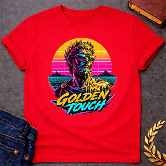 Red t-shirt with A Retro synthwave-inspired Greek mythology design featuring a stylized bust of King Midas wearing sunglasses as molten gold drips over half his face and shoulder. A vibrant neon sunset, grid landscape, and mountains create an 80s vaporwave backdrop. Bold brush lettering reads "Golden Touch" in gold and teal, using bright pink, purple, cyan, and gold for a striking vintage aesthetic.