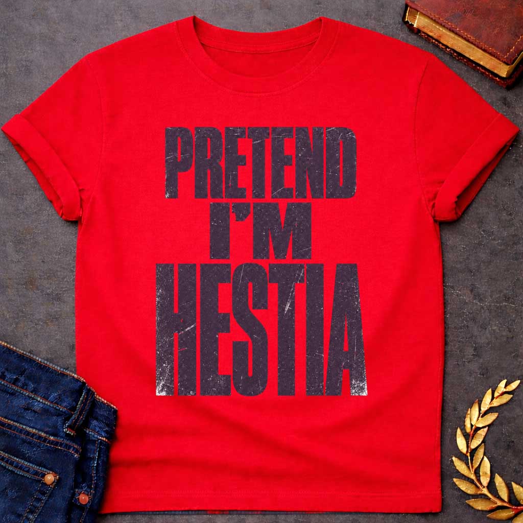 Red t-shirt with a Pretend I’m Hestia Greek mythology design featuring bold distressed dark purple typography on a transparent background. The stacked text reads “PRETEND I’M HESTIA” in a rugged vintage block font, creating a humorous design inspired by Hestia, the Greek goddess of the hearth, home, family, and domestic life.