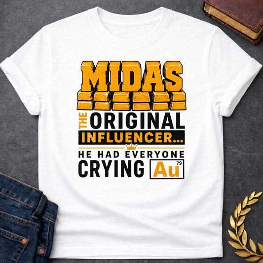 White t-shirt with A Bold typographic Greek mythology design featuring stacked gold bar lettering spelling "MIDAS" above the phrase "The Original Influencer... He Had Everyone Crying Au." The design uses distressed black and metallic gold typography with a small crown icon and a gold-themed chemical element "Au" symbol, creating a humorous King Midas pun in a vintage-inspired graphic style.
