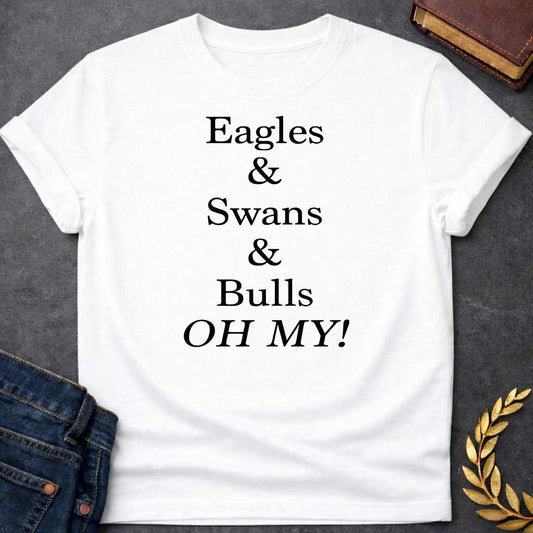 White T-shirt graphic in black featuring large bold serif text reading "Eagles & Swans & Bulls OH MY!" — a humorous parody of the "Lions and Tigers and Bears, Oh My!" phrase from The Wizard of Oz, referencing the many animal disguises Zeus used for his romantic pursuits in Greek mythology