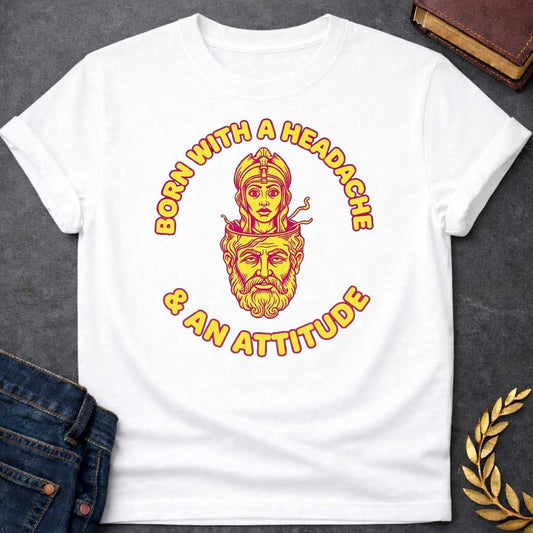 White T-shirt graphic in yellow and pink featuring a retro illustration of Athena emerging from the split-open head of Zeus, depicted as a bearded older man with his cranium open at the top. Bold rounded yellow text with pink outline curves around the circular design reading "Born with a Headache" arched above and "& an Attitude" arched below — a humorous reference to the Greek myth of Athena's birth, in a vintage biker patch style set