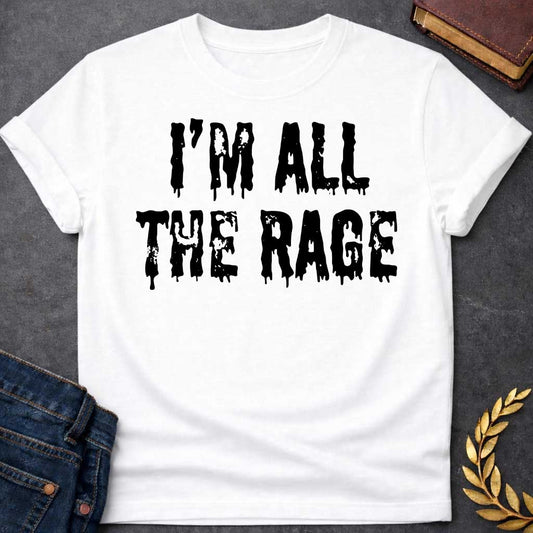 White T-shirt graphic in black featuring large dripping horror-style text reading "I'm All the Rage" — a double entendre playing on both popular trends and the furious wrath of Ares, the Greek God of War, rendered in a distressed melting font
