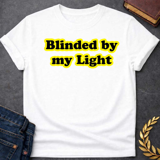 White T-shirt Streetwear graphic design featuring the phrase "Blinded by my Light" in bold black bubble typography with a vibrant yellow glow. Retro-style aesthetic inspired by Greek mythology and Apollo, the god of light
