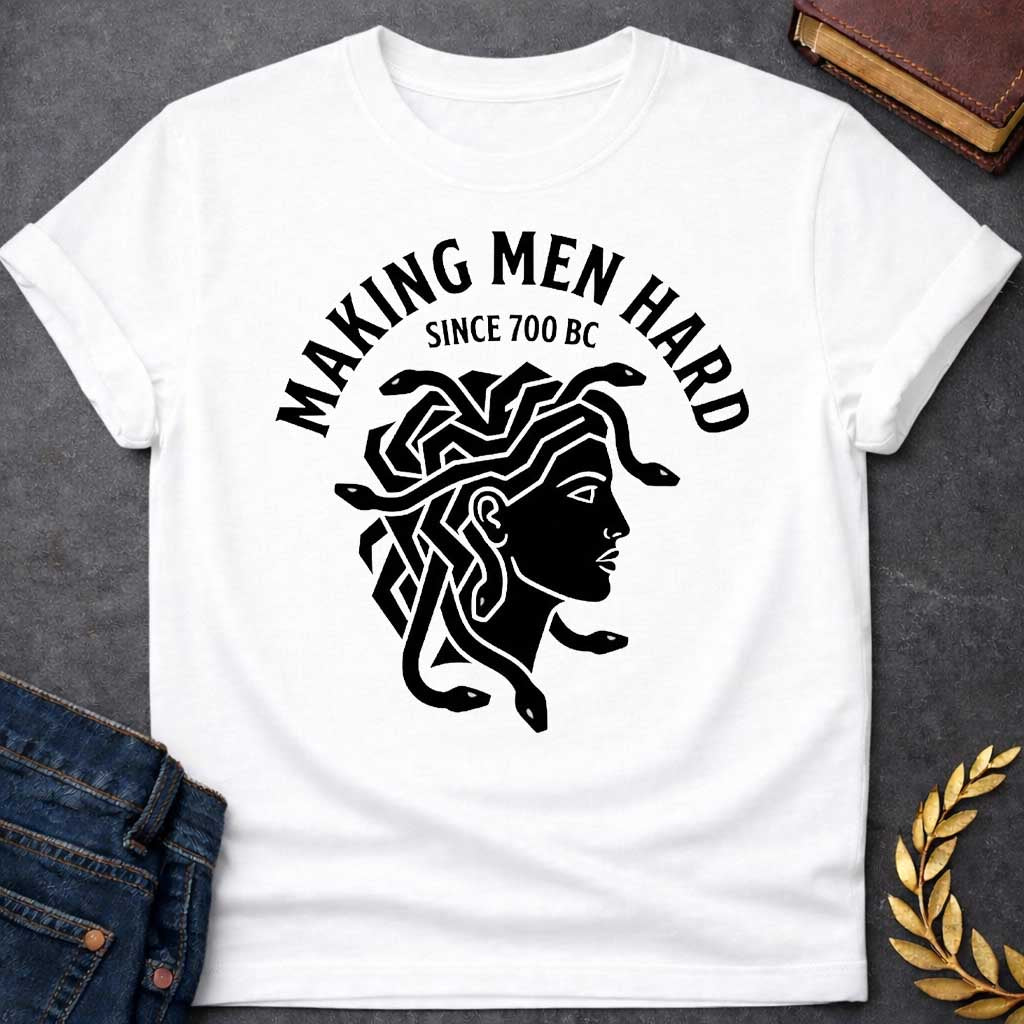 White T-shirt graphic black featuring a bold flat graphic side-profile illustration of Medusa with snake hair, in a minimalist ancient Greek coin or seal style. Bold arched text above reads "Making Men Hard" with smaller text below it reading "Since 700 BC" — a witty double entendre referencing Medusa's mythological power to turn men to stone