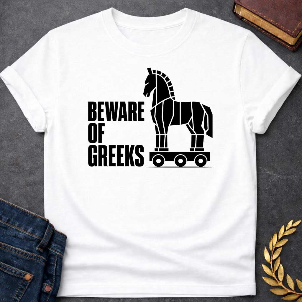 White T-shirt with a graphic in black featuring bold condensed sans-serif text reading "Beware of Greeks" alongside a flat geometric black silhouette illustration of the Trojan Horse mounted on a wheeled platform — a humorous reference to the Greek legend of the Trojan War