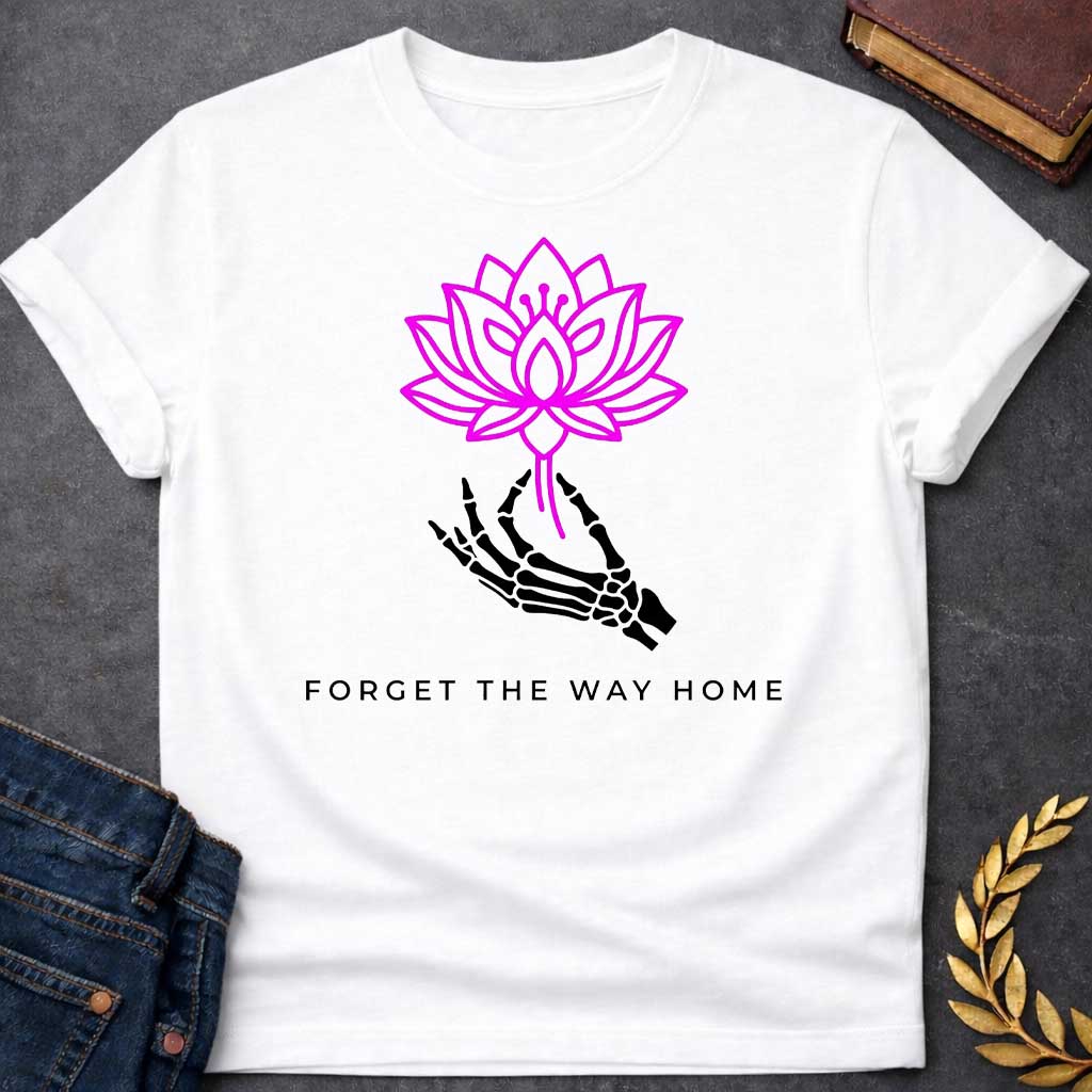 White T-shirt with a graphic featuring a bold magenta line-art lotus flower held delicately by a black skeletal hand, with spaced bold sans-serif text below reading "Forget the Way Home" — a darkly humorous reference to the Land of the Lotus-Eaters episode in Homer's Odyssey, where Odysseus's crew ate lotus flowers and forgot their desire to return home