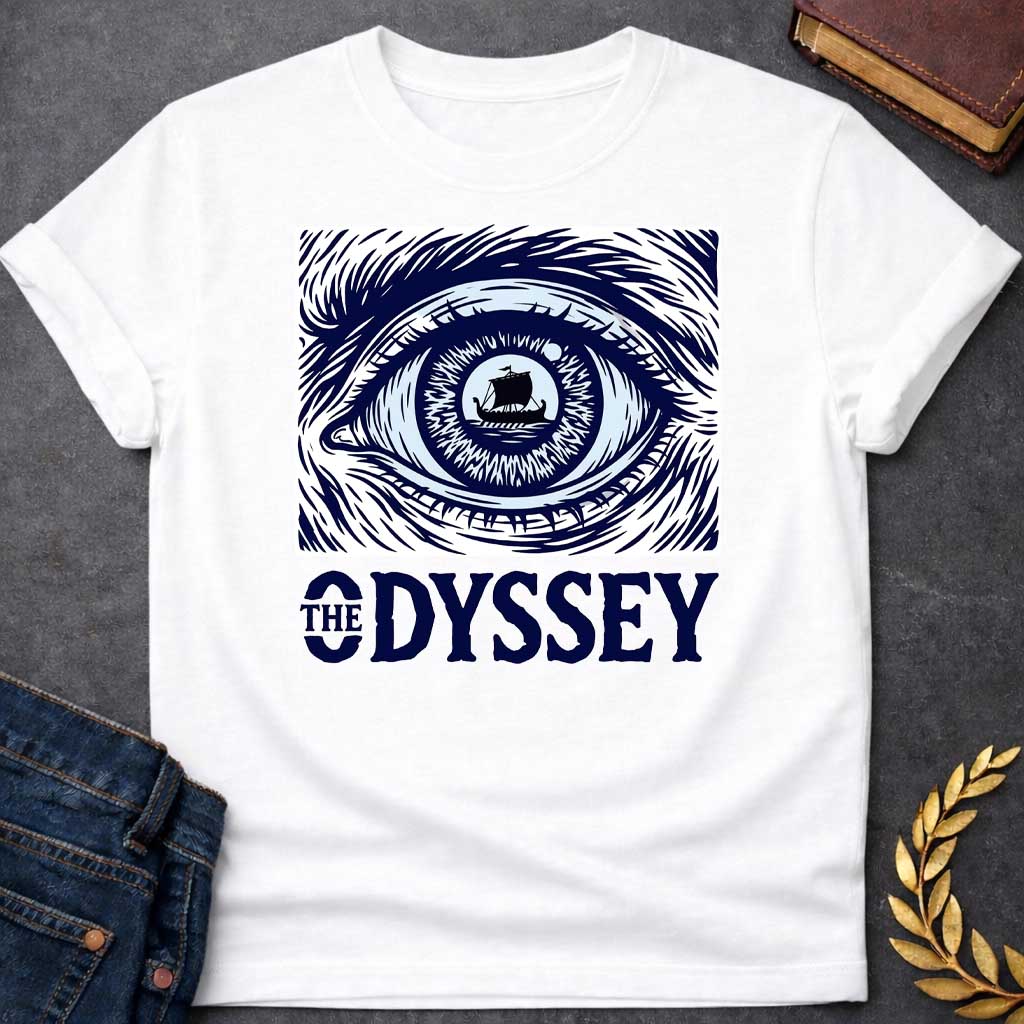 White T-Shirt with a dramatic graphic design for 'The Odyssey' featuring a stylized eye in navy blue and white. The iris contains a silhouette of an ancient Greek ship with a single sail, surrounded by radiating lines suggesting both an iris pattern and oceanic waves. Swirling, turbulent linework evokes stormy seas and Odysseus's tumultuous journey. Bold serif text reads 'THE ODYSSEY' in navy blue. Combines classical maritime imagery with modern design, emphasizing vision, journey, destiny, and fate.