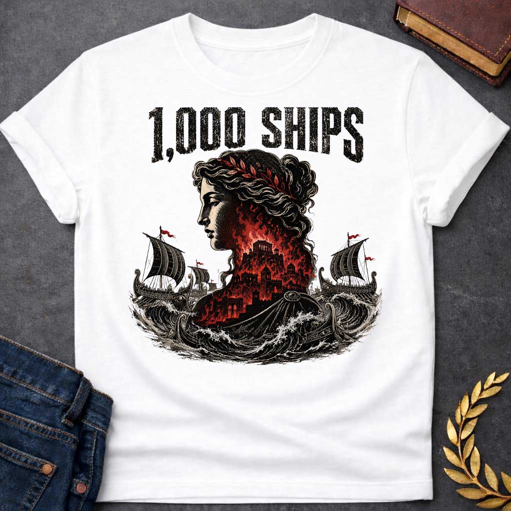 White T-shirt with a dramatic illustration of Helen of Troy in profile with curly hair and red laurel crown. Her silhouette contains the burning city of Troy in red and black flames. Greek warships with red flags sail through turbulent waves on either side. Bold distressed text reads '1,000 SHIPS' above. References the famous phrase 'the face that launched a thousand ships' describing Helen's beauty that sparked the Trojan War.