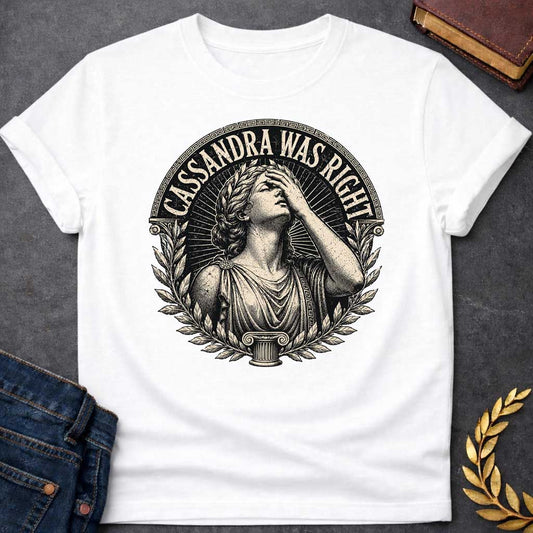 White T-shirt with a classical engraving-style illustration of Cassandra, the Trojan prophetess, looking upward with one hand raised to her forehead in anguish. She wears flowing Greek robes with decorative brooch and Greek key pattern trim. Surrounded by laurel wreaths and flanked by Ionic columns. Radiating lines create a dramatic halo effect. Text 'CASSANDRA WAS RIGHT' curves along the top within a Greek key border. References the tragic myth of Cassandra, cursed to see the future but never be believed.