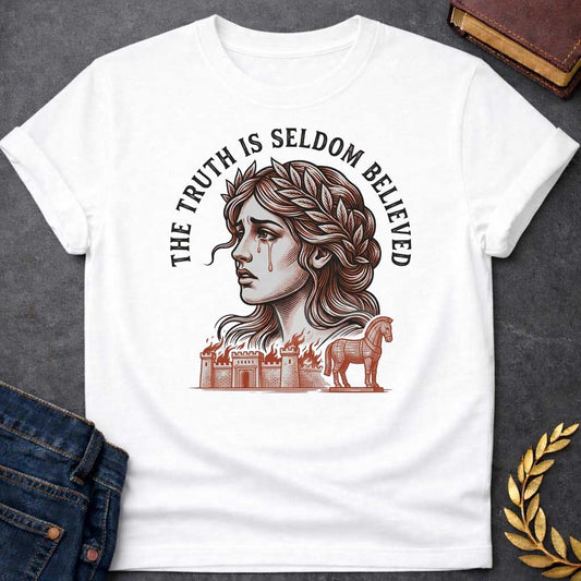 White T-shirt with a A Greek mythology design featuring a detailed woodblock-engraving style illustration of a crying Cassandra in profile. She wears a laurel wreath, with tears streaming down her face. Arched above her is the text "THE TRUTH IS SELDOM BELIEVED" in a bold black serif font. Below her portrait, a burning ancient city wall and the Trojan Horse are illustrated in a fine-line, terracotta-orange style.
