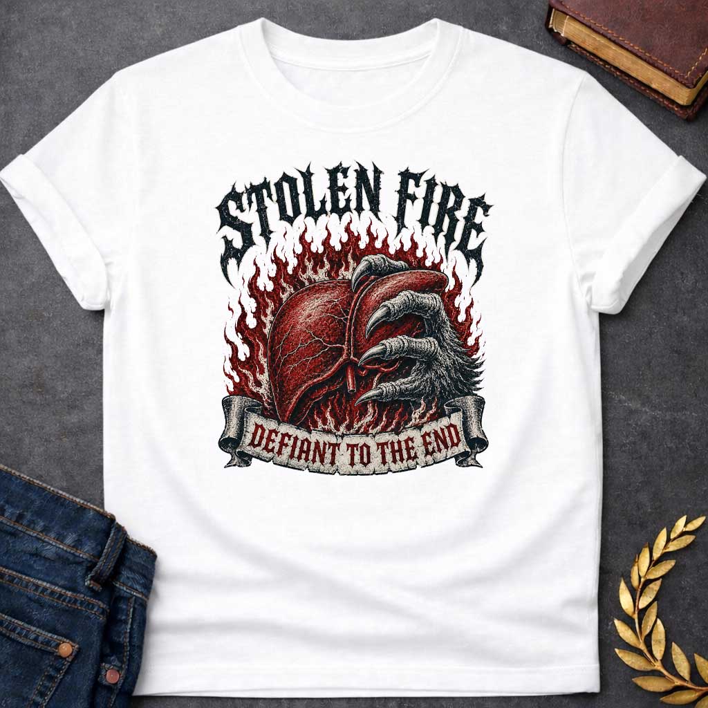 White T-shirt with a heavy metal style graphic referencing Prometheus. It features a detailed, anatomical human liver gripped tightly by a large, feathered eagle claw, set against a background of roaring red flames. At the top, the words "STOLEN FIRE" are written in a jagged, distressed black metal font. A weathered scroll banner across the bottom reads "DEFIANT TO THE END" in a sharp, red gothic typeface.