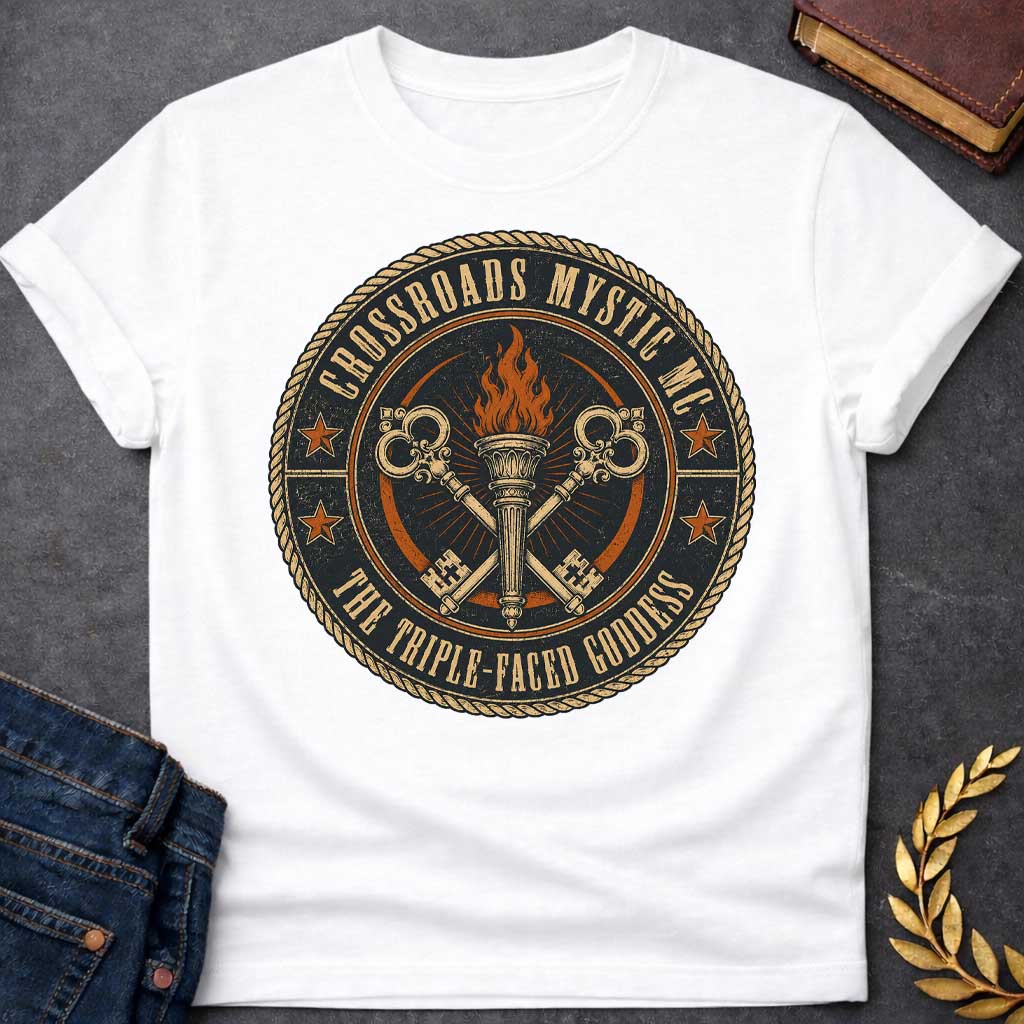 White T-shirt with a Motorcycle club patch-style emblem in navy, gold, and orange inspired by Hecate and crossroads mythology. A central ornate torch with orange flames is flanked by two crossed serpent handles with decorative gold scrollwork. Radiating lines suggest divine power. Text reads 'Crossroads Mystic MC' and 'The Triple-Faced Goddess' around the border. Orange stars and rope border complete the official club patch look. Distressed texture adds authentic biker aesthetic.