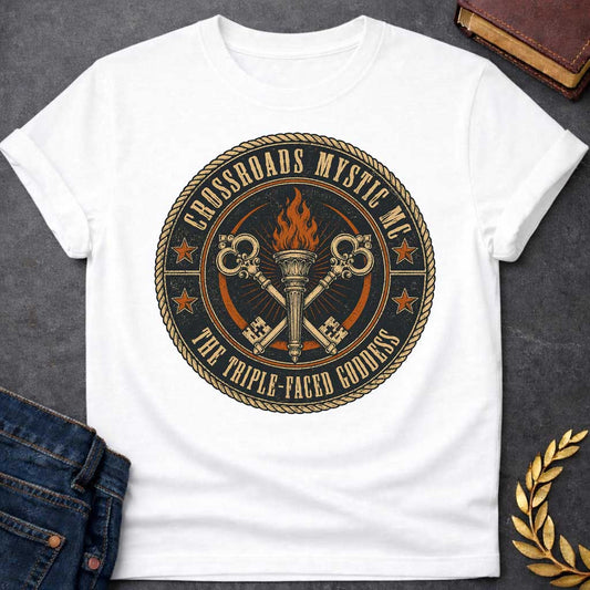 White T-shirt with a Motorcycle club patch-style emblem in navy, gold, and orange inspired by Hecate and crossroads mythology. A central ornate torch with orange flames is flanked by two crossed serpent handles with decorative gold scrollwork. Radiating lines suggest divine power. Text reads 'Crossroads Mystic MC' and 'The Triple-Faced Goddess' around the border. Orange stars and rope border complete the official club patch look. Distressed texture adds authentic biker aesthetic.