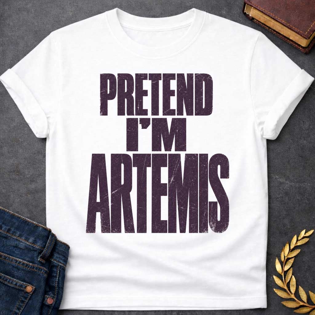 White t-shirt with a Pretend I’m Artemis Greek mythology design featuring bold distressed purple typography on a transparent background. The stacked text reads “PRETEND I’M ARTEMIS” in a rugged vintage block font, creating a humorous design inspired by Artemis, the Greek goddess of the hunt, wilderness, wild animals, archery, and the moon.