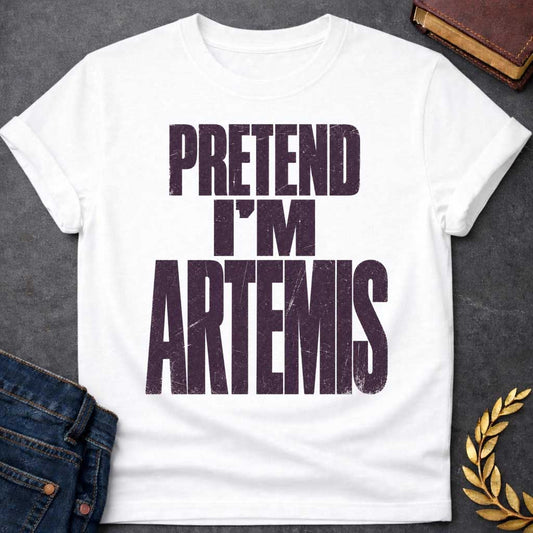 White t-shirt with a Pretend I’m Artemis Greek mythology design featuring bold distressed purple typography on a transparent background. The stacked text reads “PRETEND I’M ARTEMIS” in a rugged vintage block font, creating a humorous design inspired by Artemis, the Greek goddess of the hunt, wilderness, wild animals, archery, and the moon.