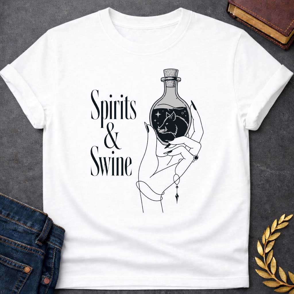White T-shirt with a Minimalist line art illustration of a mystical hand holding a potion bottle labeled 'Spirits & Swine.' Inside the dark bottle, a pig silhouette appears amid glowing stars and magical elements. The elegant hand wears decorative bracelets and rings. Black and white aesthetic with witchy, occult vibes. References Circe's legendary enchanted spirits that transformed men into swine. Celebrates ancient magic, potion-making, and mythological transformation with modern witchcraft themes.