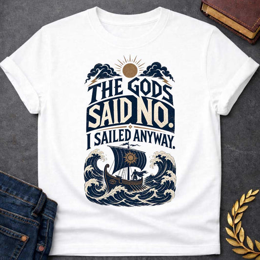 White t-shirt with a Vintage Greek mythology design featuring the bold phrase “The Gods Said No. I Sailed Anyway.” An ancient Greek ship battles towering ocean waves beneath storm clouds, lightning bolts, and a glowing sun. Distressed navy, cream, and gold artwork captures the defiant spirit of Odysseus and The Odyssey.

