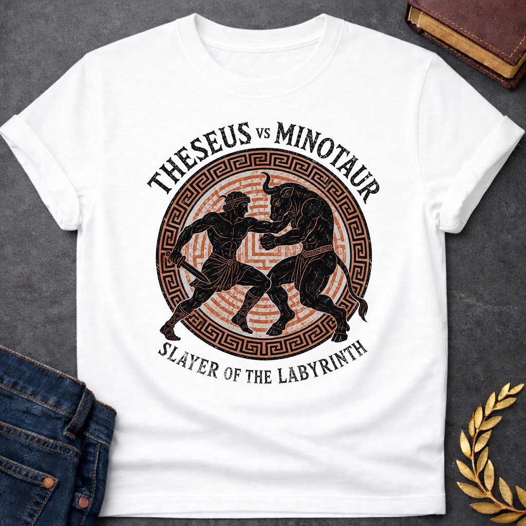 White T-shirt with A vintage, Greek pottery-style graphic depicting a battle. At the center, the muscular hero Theseus holds a sword as he wrestles the powerful Minotaur. The black figure silhouettes are set against an orange labyrinth pattern inside a circular frame with a Greek key border. Distressed text reads "THESEUS VS MINOTAUR" arched across the top and "SLAYER OF THE LABYRINTH" curved along the bottom.