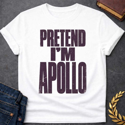 White t-shirt with a Pretend I’m Apollo Greek mythology design featuring bold distressed purple typography on a transparent background. The stacked text reads “PRETEND I’M APOLLO” in a rugged vintage block font, creating a simple humorous design inspired by Apollo, the Greek god of the sun, music, poetry, prophecy, and healing.