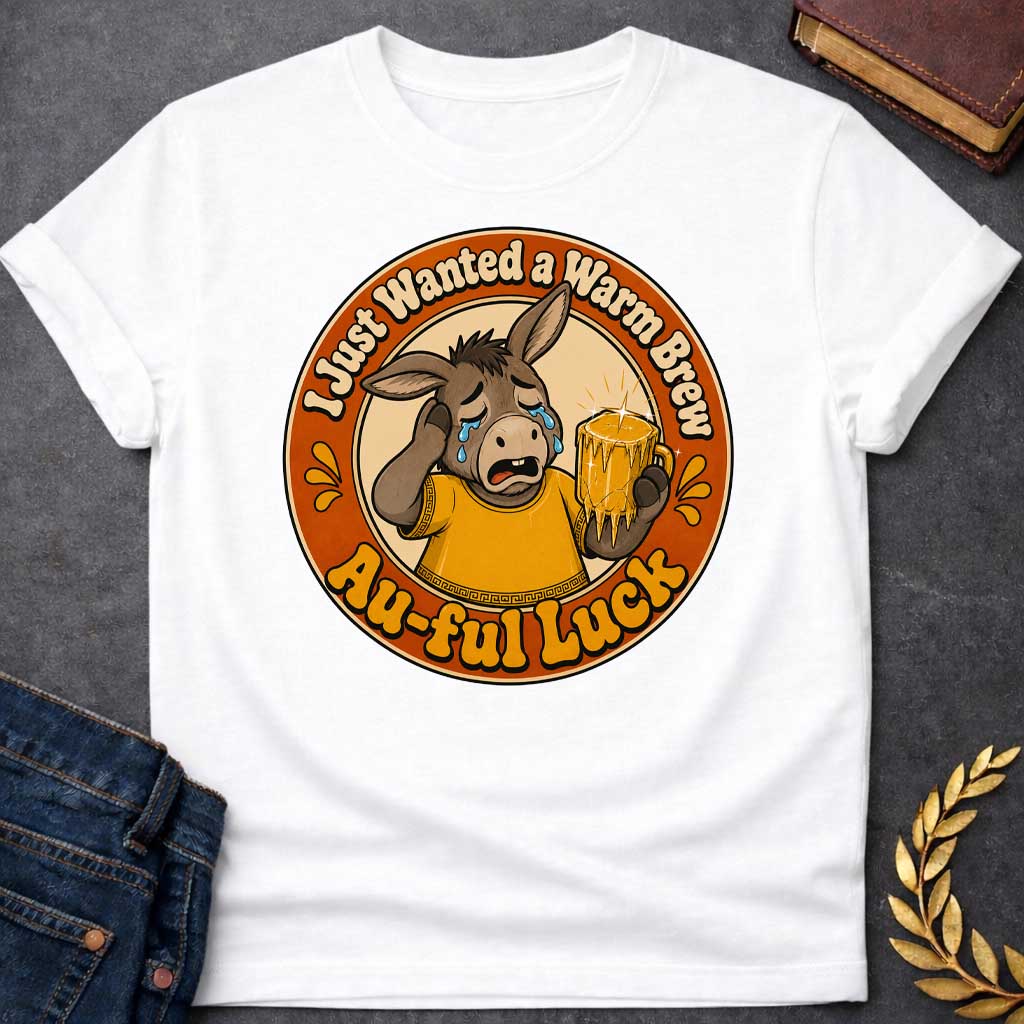 White t-shirt with A Funny Greek mythology design featuring a crying cartoon donkey wearing a gold ancient Greek tunic and holding a dripping gold beer mug. Circular vintage badge layout with the humorous text, "I Just Wanted a Warm Brew" at the top and "Au-ful Luck" at the bottom, referencing the myth of King Midas. Retro orange, gold, cream, and brown color palette with bold, distressed vintage styling.