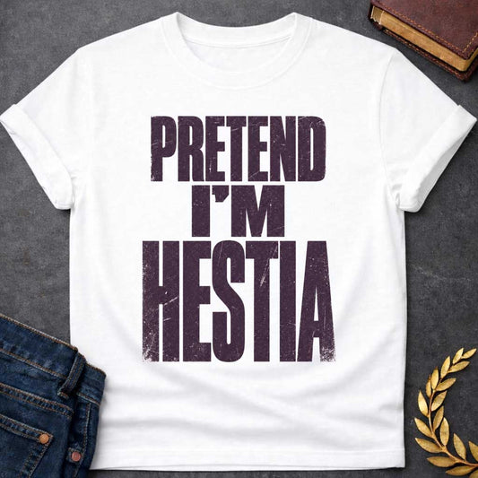 White t-shirt with a Pretend I’m Hestia Greek mythology design featuring bold distressed dark purple typography on a transparent background. The stacked text reads “PRETEND I’M HESTIA” in a rugged vintage block font, creating a humorous design inspired by Hestia, the Greek goddess of the hearth, home, family, and domestic life.
