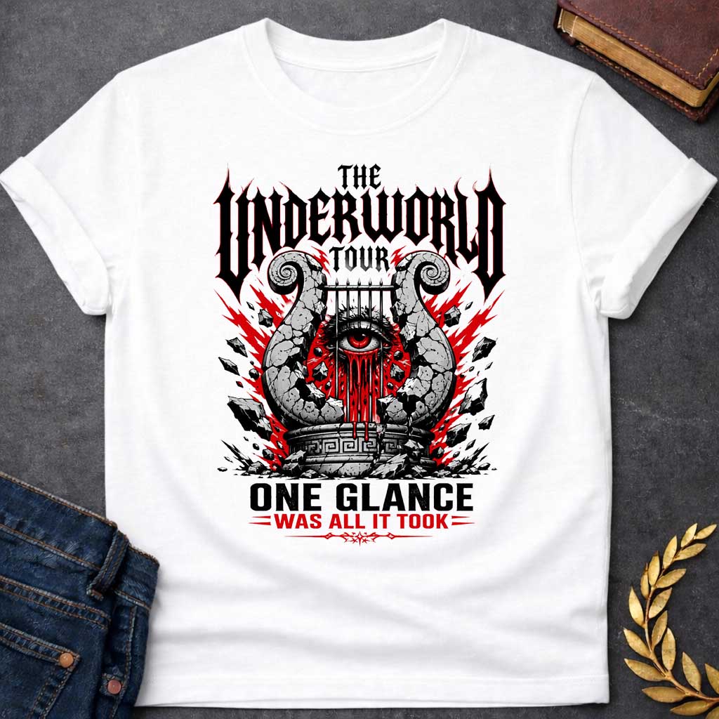White t-shirt in heavy metal band-poster style: a cracked stone lyre with a bleeding red eye at its center sits atop a Greek pedestal, framed by jagged red lightning bolts and scattered rubble. Gothic spiked black lettering and bold red accent text complete the design