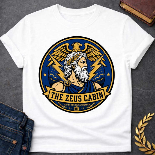 White t-shirt with a Zeus Greek mythology cabin design featuring the bearded god of the sky and thunder with a laurel crown, golden eagle, lightning bolts, storm clouds, and Greek temple symbol. Bold blue, gold, white, and black circular camp-style emblem includes the text “The Zeus Cabin” and “God of the Sky & Thunder.”