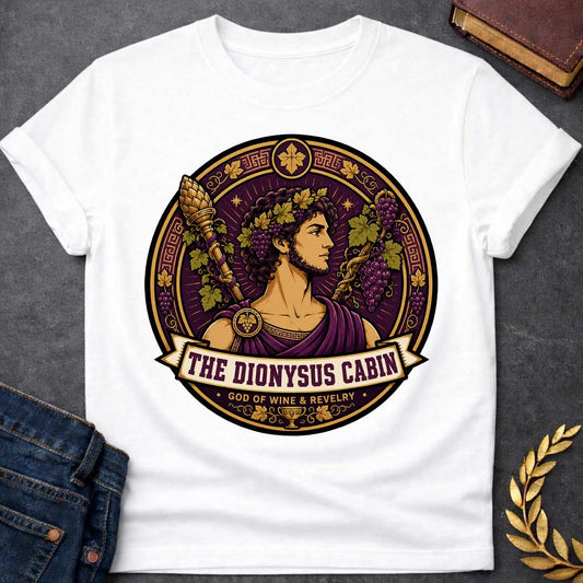 White t-shirt with a Dionysus Greek mythology cabin design featuring the god of wine and revelry wearing a grapevine crown and purple robes, surrounded by clusters of grapes, vine leaves, a thyrsus, Greek key patterns, and a wine cup. Purple and gold circular emblem includes the text “The Dionysus Cabin” and “God of Wine & Revelry,”