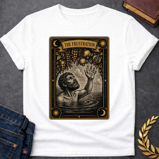 White t-shirt with A detailed tarot card-style illustration. Set within an ornate black and gold border featuring sun and moon corner emblems, a bearded man in rippling water reaches one hand up toward hanging branches overflowing with grapes and pomegranates. A ribbon banner across the top of the card displays the title "THE FRUSTRATION" in a bold serif typeface.